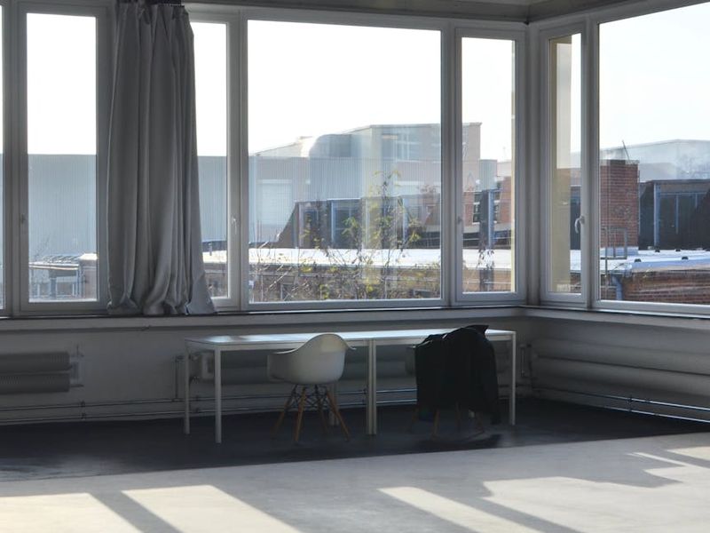 Spacious, sunlit studio with wooden floors and large windows.