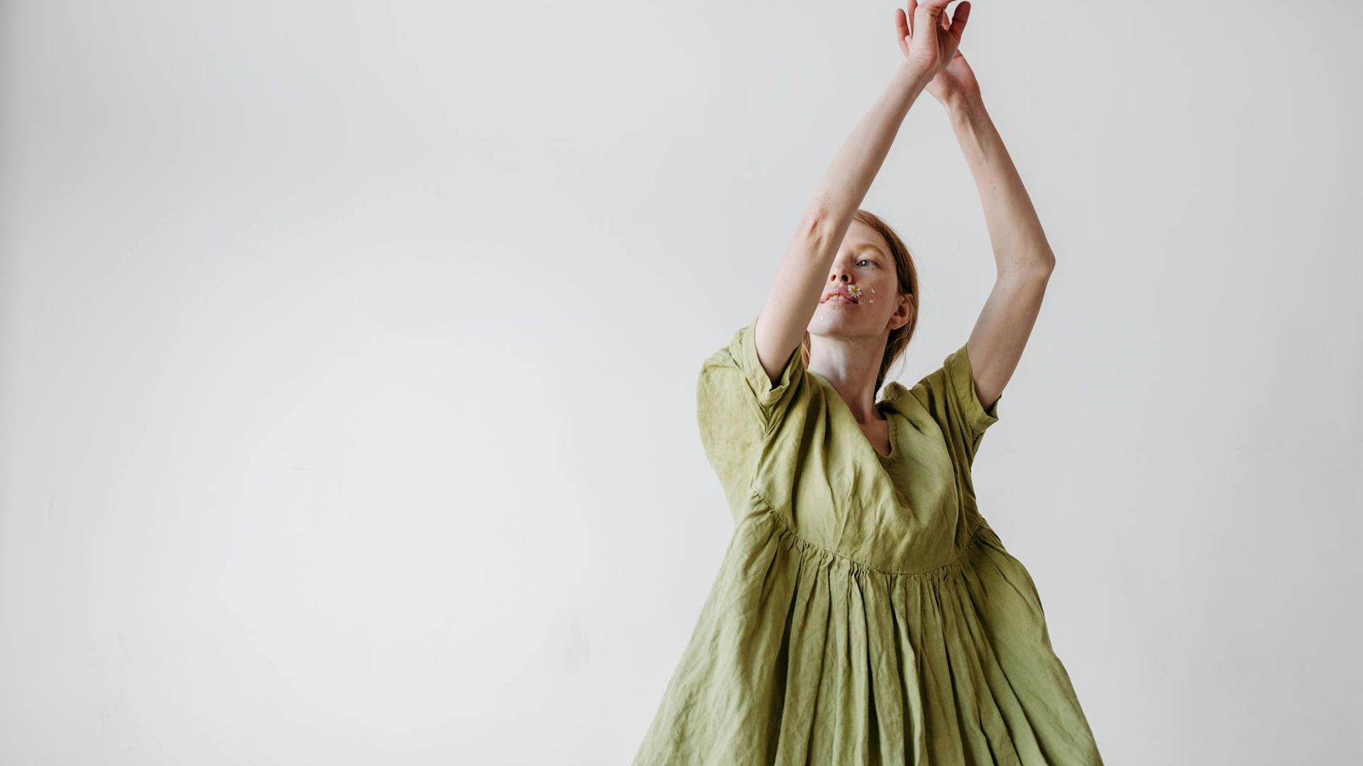Woman in a calm, flowing movement pose in a minimalist studio.
